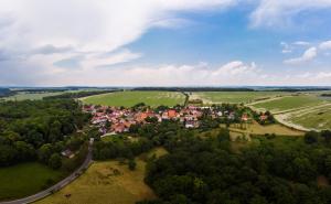 Luftbildaufnahme von Closewitz Richtung Weimar: im Vordergrund grüne Ackerflächen und kleine Waldlandschaften, gefolgt von der Siedlung mit Häusern, dann folgen grüne Ackerflächen und ein blauer Himmel mit Schleierwolken