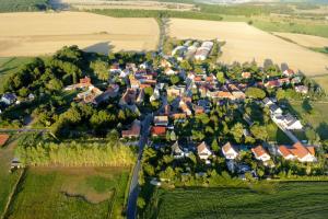Luftbildaufnahme von Lützeroda: Im Vordergrund sind grüne Ackerflächen, gefolgt von der Siedlung mit Häusern, gefolgt von landwirtschaftlichen Nutzflächen, dahinter grüne Wiesen und Waldgrundstücke