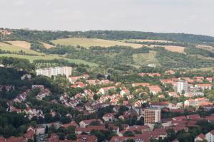 Luftbildaufnahme Jena-Nord: im Vordergrund sind viele Mehrfamilienhäuser, gefolgt von grünen Wiesen und dem Jägerberg mit Waldlandschaft