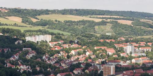 Luftbildaufnahme Jena-Nord: im Vordergrund sind viele Mehrfamilienhäuser, gefolgt von grünen Wiesen und dem Jägerberg mit Waldlandschaft
