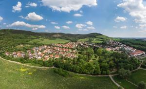 Luftbildaufnahme von Drackendorf: im Vordergrund sind grüne Wiesen und der Park von Drackendorf, gefolgt von der Siedlung mit Häusern und den Kernbergen im Hintergrund