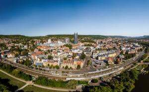 Luftbildaufnahme von Jena-Zentrum aus Südrichtung: Im Vordergrund ist der Stadtpark Paradies gefolgt vom Paradies-Bahnhof, dann folgt die Innenstadt mit vielen Häusern, der Jentower und anschließend der Landgraf