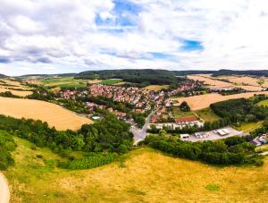 Luftbildaufnahme von Jenaprießnitz/Wogau: Im Vordergrund sind grüne Ackerflächen sowie landwirtschaftliche Nutzflächen gefolgt von der Siedlung mit Häusern, dann folgen grüne Ackerflachen, landwirtschaftliche Nutzflächen und Waldflächen