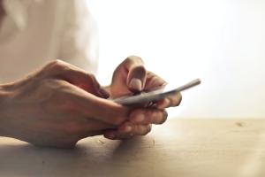 Hände halten Smartphone und tippen darauf