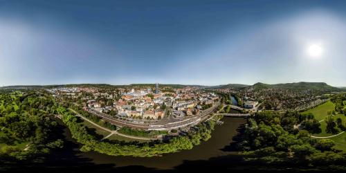 Blick auf eine Stadt, die idyllisch im Grünen und an einem Flussufer gelegen ist