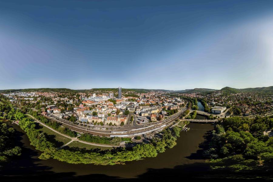 Blick auf eine Stadt, die idyllisch im Grünen und an einem Flussufer gelegen ist