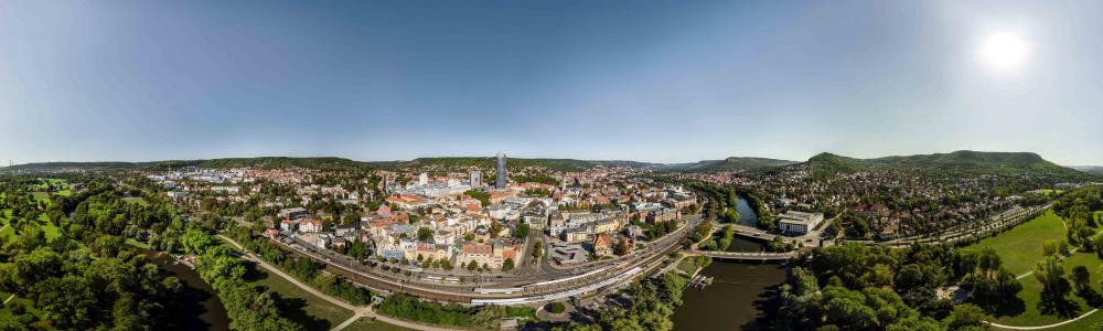 Blick auf eine Stadt, die idyllisch im Grünen und an einem Flussufer gelegen ist